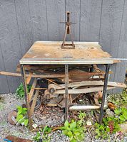 Full view of steel welding table with stainless steel top and rusted metal items underneath