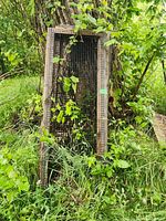 Four wood and wire mesh panels leaning outdoors against natural log and greenery, showing size and condition