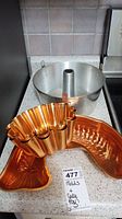 Set of three cake and jelly molds placed on a kitchen counter including one aluminum bundt pan and two copper-colored molds.