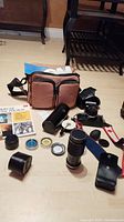 Overview of camera body, lenses, flash, camera bag and accessories laid out on floor.