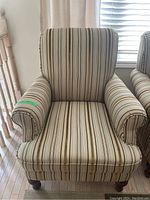 Front view of armchair showing striped fabric upholstery and padded arms.
