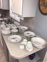 Multiple bowls, plates, teacups, gravy boat, and coffee pot arranged on countertop