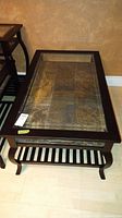 Photo showing top angle of rectangular coffee table with glass top and stone style shelf beneath
