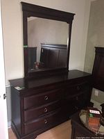 Full front view of dark wooden dresser with attached large mirror, showing overall size and style
