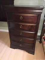Full view of wooden dresser showing all five drawers and metal ring pull handles.
