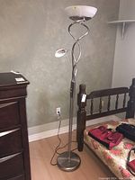 Full view of the metal floor lamp showing the spiral twin-arm design, round base, and both lamp shades.