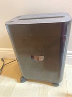 Front and side view of the black shredder unit on caster wheels showing overall shape and structure.