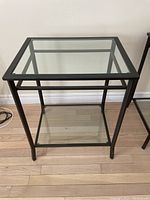 Full view of metal and glass side table, showing lower glass shelf and metal frame.