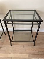 Front angled view of the metal and glass side table showing design and structure.