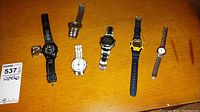 Photo of six assorted watches laid out on wood surface