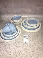 Full set of Wedgwood porcelain dinnerware including multiple plates, bowls, and teacups arranged on a countertop, showing overall grouping and brand tag.