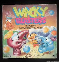 Front view of Wacky Blasters board game box showing colorful cartoon characters and puff balls for ages 6 and up