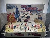 Front view of the complete Top Corner tabletop hockey game with original box in background