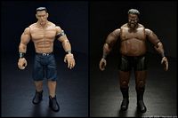 Two WWE wrestling action figures John Cena and Mark Henry posed side-by-side on black surface with black background.