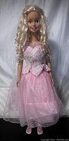Full view of the Barbie doll showing the full length pink dress and blond curly hair.