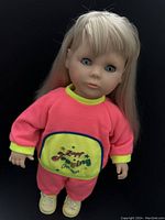 Front view of the 1980s Balica Zapf Creation doll with blonde hair, blue eyes, pink and yellow outfit, and yellow shoes.