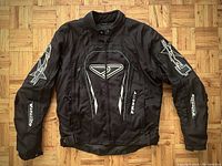 Front view of black Foxstar Velocity motorcycle jacket showing logos and design details.
