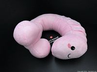 Photo of new adult novelty pink plush neck pillow with smiling face, showing full pillow shape and texture.