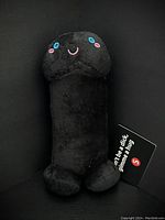 Front side of the black adult novelty plushie showing face and tag.