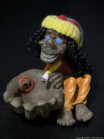 Novelty ash tray figurine of a man with rasta style hat, sunglasses, curly hair, holding an ash tray with a no-smoking sign and a cigar.