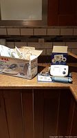 View of both T-Fal Advantis 90 steam iron in original box and Life Source blood pressure monitor with accessories displayed on countertop.