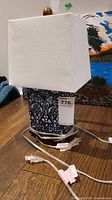 Front view of the ceramic table lamp showing the blue and white floral patterned base and rectangular white fabric shade with an electrical cord.