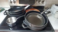 Photo showing top view of fry pans and small pot on stove, arranged with handles visible