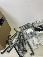 Various black and metallic cabinet handles and hooks, some sealed in original packaging.