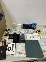 All electronic accessories including cell phone cases, watch bands, charging devices and adapters shown on table in initial photo