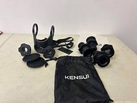 Full view of Kensui workout accessories including cup holder, threaded nuts, rubber pads, and pouch arranged on table.