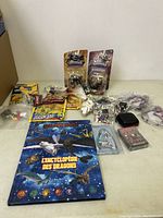 Overview of lot showing LEGO pieces, Skylander figures, dragon book, cards, and other items