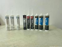 Photo showing 10 tubes of silicone and adhesive products from different brands including Proflo, Sikaflex, Quad Max, and AD Seal arranged in a row on a table.