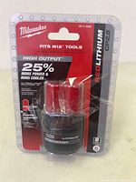 Front view of Milwaukee M12 RedLithium CP2.5 battery in packaging showing brand, label, and power output claims.