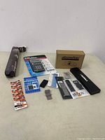 Lot overview showing a variety of items including watch bands, calculator, battery, SIM cards, and small miscellaneous items.