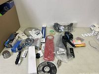 Wide view of assorted automotive and tool components including Black Hawk grinding disc, metal parts, and electrical panel component.