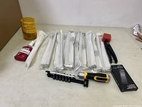 Photo showing DeWalt screwdriver with bit holder and multiple unopened bundles of white zip ties, Loctite adhesive, red brush and yellow container.