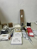 Various miscellaneous tools and hardware spread out on a surface including boxes, a wrench, Knipex box, and other components.