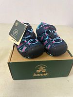 Front angle view of Kamik toddler sandals on Kamik shoe box, showing closed toe design and color details.