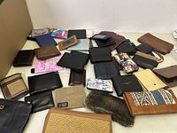 Wide view showing all wallets laid out on a table with various colors, patterns, and materials visible