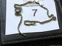 Silver-tone rope chain necklace arranged to show clasp and chain detail on dark background.