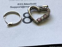 Two jewelry pieces: a multi-colored gemstone heart-shaped pendant and a small 10K gold hoop earring on a white paper background.