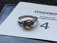 Front view of 10k gold ring showing three round rubies set horizontally with small diamonds on the sides.