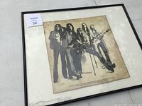 Framed Alice Cooper album cover with sepia band photo and visible wear, displayed on a white surface with framed glass reflecting light.
