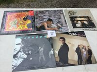 Top view of five soft rock vinyl albums arranged on the ground showing their front covers including Santana and Peter Frampton.