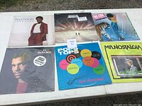 Top view of six vinyl album covers including Billy Ocean, Journey, El DeBarge, The Tara Showband, Mr. Nostalgia, and Pop Tops.