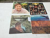 Four Buck Owens vinyl album covers arranged on a flat surface; visible front covers include portraits and varied imagery with album titles readable