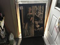 Large framed artwork featuring three black and white photos of Marilyn Monroe in different poses, set against a dark frame.