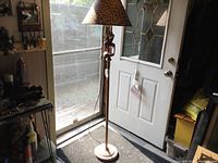 Full view of the wooden floor lamp showing the base, stand with carved giraffes, and leopard print lampshade.