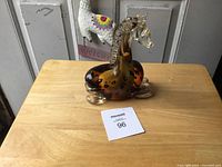 Photo of the amber-colored, heavy ornamental glass giraffe on a wooden surface showing the full body and detailed neck.