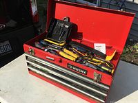 Red Husky tool box open showing top tools including drill bit set, pliers, wrenches, crowbar and screwdrivers